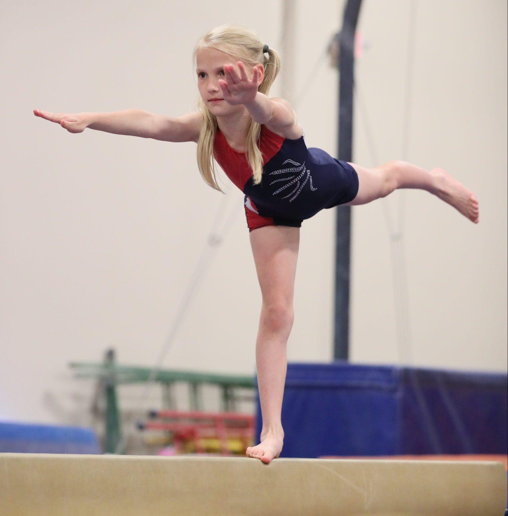 Girl doing an arabesque on beam at Legends Gymnastics in North Andover, MA.